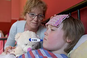 Cold And Flu Season Drucke: Mother comforts sick son in bed