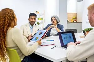 Business Professionals Working Together Drucke: Multiethnic business professionals collaborating around a table
