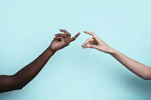 Diversity And Inclusion Drucke: Two multiethnic hands reach toward each other against a solid blue backdrop