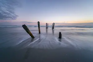 Old Broken Bridge Drucke: Old broken bridge, posts in the water on the beach at dusk