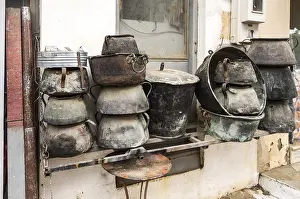 Old Building Exterior Drucke: Several old cauldrons in heap in front of a facade