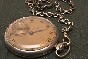 Close Up Clock Drucke: Very old clock with chain lying on rough green surface