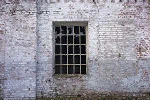 Weathered Brick Wall Drucke: An old, weathered brick wall with a broken window