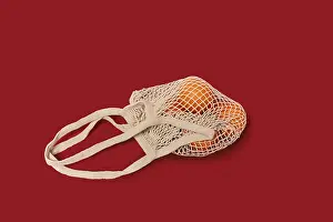 High Angle View Of Oranges Drucke: Oranges in a string bag on ruby red background