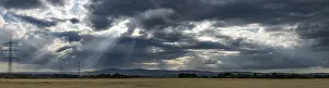 Cloudy Weather Forecast Drucke: Panorama of a dramatic sky with sunbeams and fields in the foreground