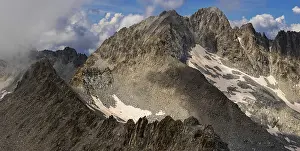 Rugged Mountain Landscape Drucke: A panoramic view of a rugged mountain range partially covered by clouds