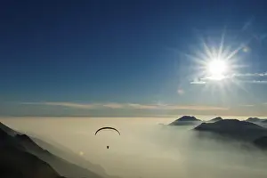 Paraglider Over Water Drucke: Paraglider over the mountains in clouds
