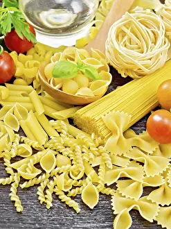 Wooden Board Background Drucke: Pasta seashells in spoon, pipe rigate