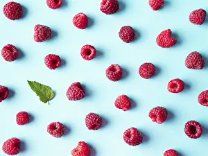 Flat Lay Fruit Photography Drucke: Pattern of ripe red raspberry on blue background