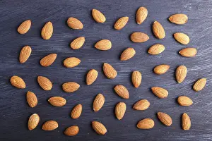 Black Wooden Background Drucke: Pattern and texture made from almonds on black wooden background