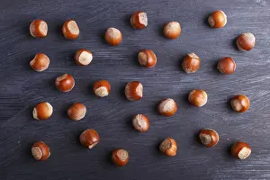 Black Wooden Background Drucke: Pattern and texture made from hazelnuts on black wooden background