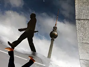 Urban Germany Photography Drucke: Pedestrian and telecommunications tower reflected in a puddle