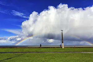 Deserted Irish Beach Drucke: Pedestrians on seafront, dramatic cloudy sky with rainbow