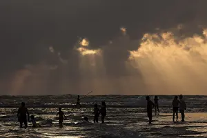 Cloudy Day At The Sea Drucke: People in backlight on beach, rays of sunlight