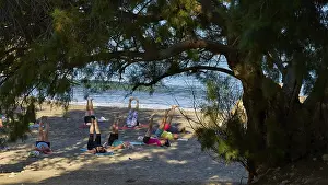 Drucke von Menschen, die Yoga unter einem Baum am Strand praktizieren, Matala, Südküste, Kreta, Griechische Inseln, Griechenland Matala Drucke: Menschen, die Yoga unter einem Baum am Strand üben.