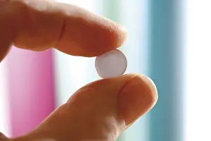 Medical Care Photo Drucke: Pill held between two fingers