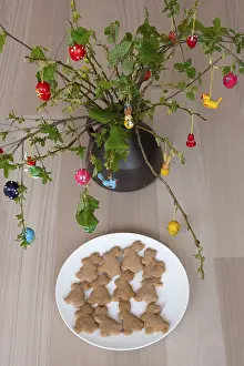Easter Food Still Life Drucke: Plate of homemade Easter bunny biscuits in front of a shrub with Easter decorations
