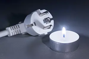 Burning Candle Image Drucke: There is a plug next to a burning candle that glows in the dark
