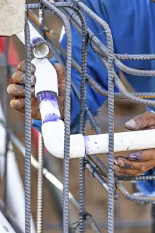 Construction Site Worker Drucke: Plumber installing PVC pipe at construction site