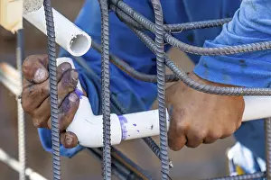 Construction Site Worker Drucke: Plumber installing PVC pipe at construction site