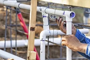 Real Estate Market Development Drucke: Plumber using level while installing PVC pipe at construction site