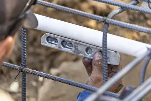 Deserted Construction Area Drucke: Plumber using level while installing PVC pipe at construction site