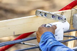 Deserted Construction Area Drucke: Plumber using level while installing PVC pipe at construction site