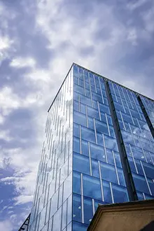 Glass Facade Architecture Drucke: Pointed modern skyscraper with glass facade under dramatic sky