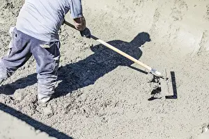 Cement Finishing Techniques Drucke: Pool construction worker working with A bullfloat on wet concrete