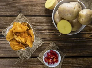 High Calorie Meal Drucke: Portion of crispy Potato Chips (selective focus) on wooden background