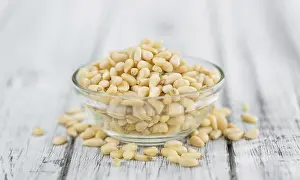 Rustic Wooden Background Image Drucke: Portion of fresh Pine Nuts (close-up shot)