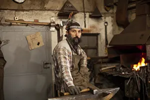 Blacksmith At Work Drucke: The portrait of bearded blacksmith preparing to work in his workshop