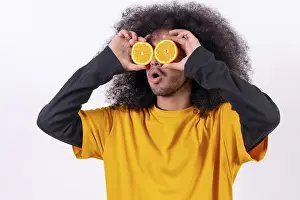 Young Man With Afro Hair Drucke: Portrait with the orange fruit in the eyes split in half
