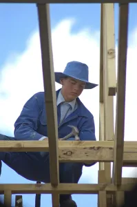 Young Construction Worker Drucke: Apprentice builder using hammer on building site