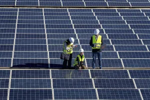 Solar Panel Inspection Drucke: Three engineers inspect a large solar panel array together