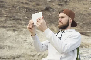 Tablet Pc Usage Drucke: Hipster with a beard in a cap