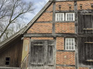 Half Timbered Construction Method Drucke: A rustic half-timbered house with bricks and small windows that indicate an ancient construction method
