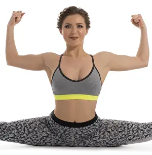 Caucasian Woman Exercising Drucke: Pretty brunette in top and leggings making split in studio