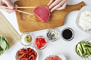 Drucke von Das Prozess der Zubereitung von Sushi, die Vorbereitung aller Zutaten für Sushi, die Mädchen hält Thunfisch mit Reisstäbchen Thunfisch Drucke: Der Prozess der Zubereitung von Sushi.