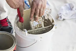 Construction Site Images Drucke: Professional painter loading paint onto his brush from A bucket
