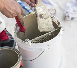 Professional Painter Drucke: Professional painter loading paint onto his brush from A bucket