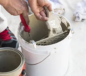 Professional Painter Drucke: Professional painter loading paint onto his brush from A bucket