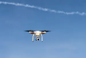 Germany Aerial View Drucke: Quadcopter with camera flying in front of a blue sky