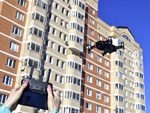 Unmanned Aerial Vehicle UAS Drucke: Quadrocopter flies in the sky and hands with a control panel