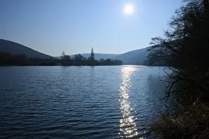 Hilly Countryside Europe Drucke: A quiet river on which the sun is reflected