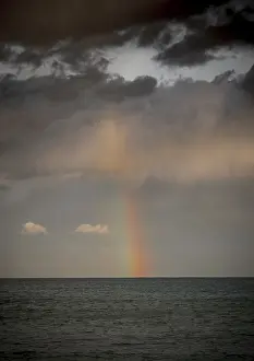 Prismatic Colors In Nature Drucke: Rainbow with dark clouds over the sea