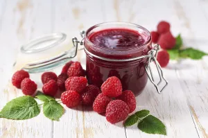 Homemade Preserves Drucke: Raspberry jam with fresh berries on a white table
