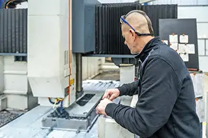 Quality Control Engineer Drucke: Rear view of an engineer working in a milling cnc machine