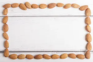 Vegetarian Meal Idea Drucke: Rectangular frame made from almonds on white wooden background