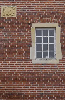 Red Brick Facade Drucke: A rectangular window and a coat of arms in a red brick facade